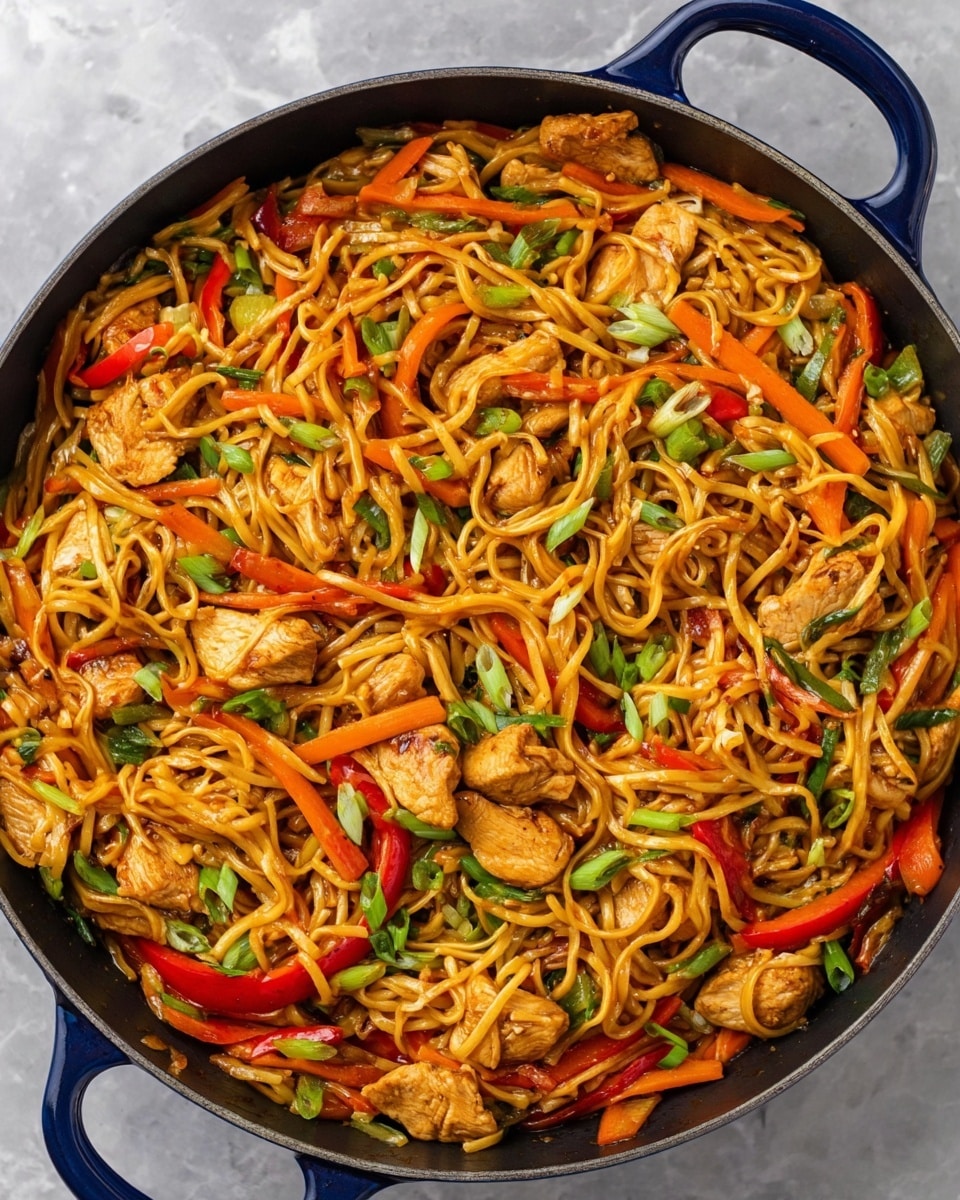 The image shows a large pan filled with stir-fried noodles mixed with colorful vegetables and pieces of chicken. The base layer is light brown stir-fried noodles, mixed with bright orange carrot sticks and red bell pepper strips evenly spread throughout. Chunks of cooked chicken are scattered on top and throughout the noodles, showing a golden brown color. Small slices of green onions are sprinkled across the whole dish, adding pops of green color. The pan is dark colored with a deep blue handle, and it sits on a white marbled surface. The food looks well mixed with a glossy, slightly oily texture. Photo taken with an iphone --ar 4:5 --v 7