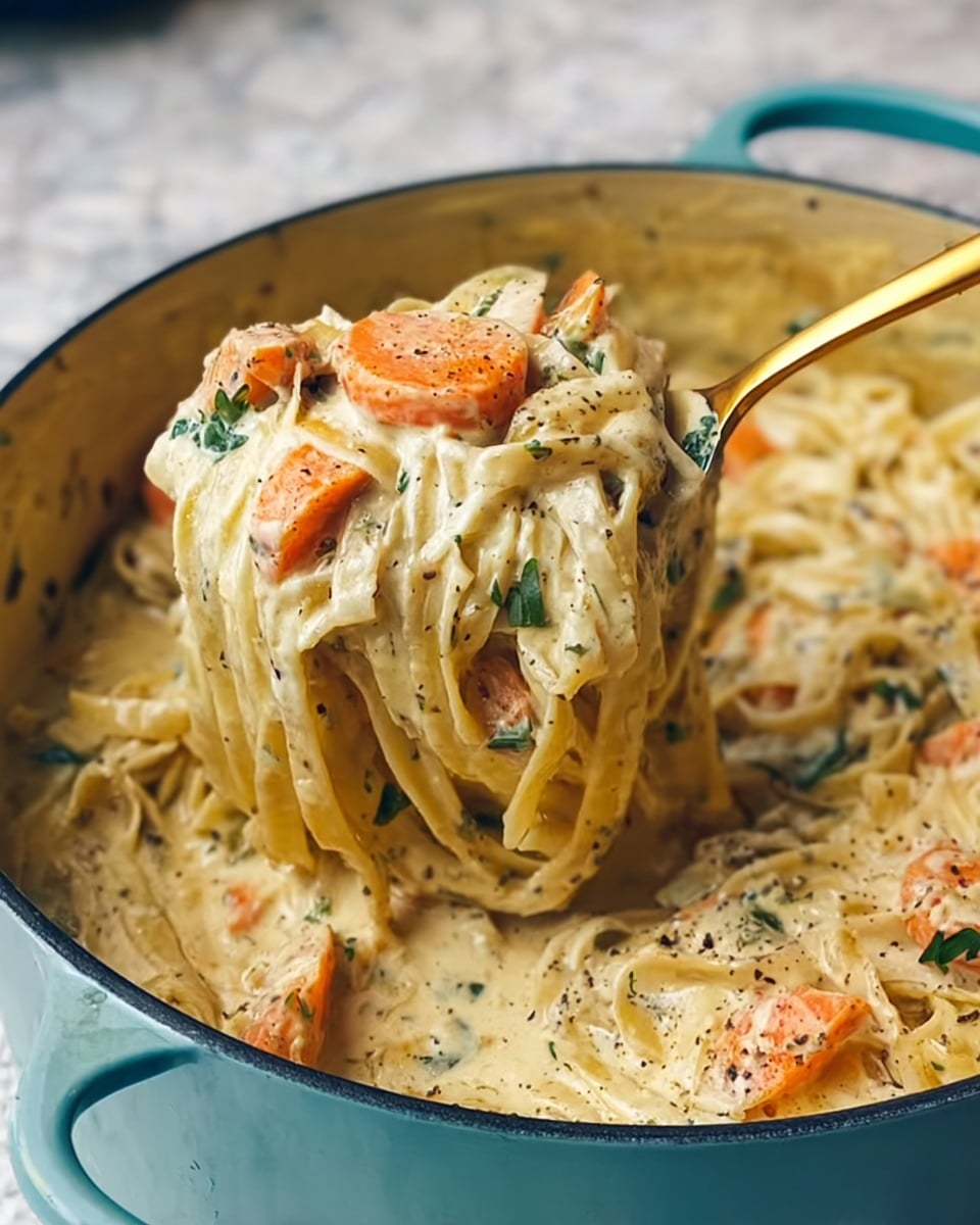 A close-up of a light blue pot filled with creamy pasta in a thick, pale yellow sauce, speckled with herbs and pepper. The pasta is long and flat, mixed with chunks of soft orange carrots and green herb leaves scattered throughout. A gold spoon lifts a portion of pasta from the pot, showing the rich sauce clinging to the noodles and carrots. The pot sits on a table with a white marbled texture underneath, with soft natural light highlighting the creamy textures and colors. photo taken with an iphone --ar 4:5 --v 7