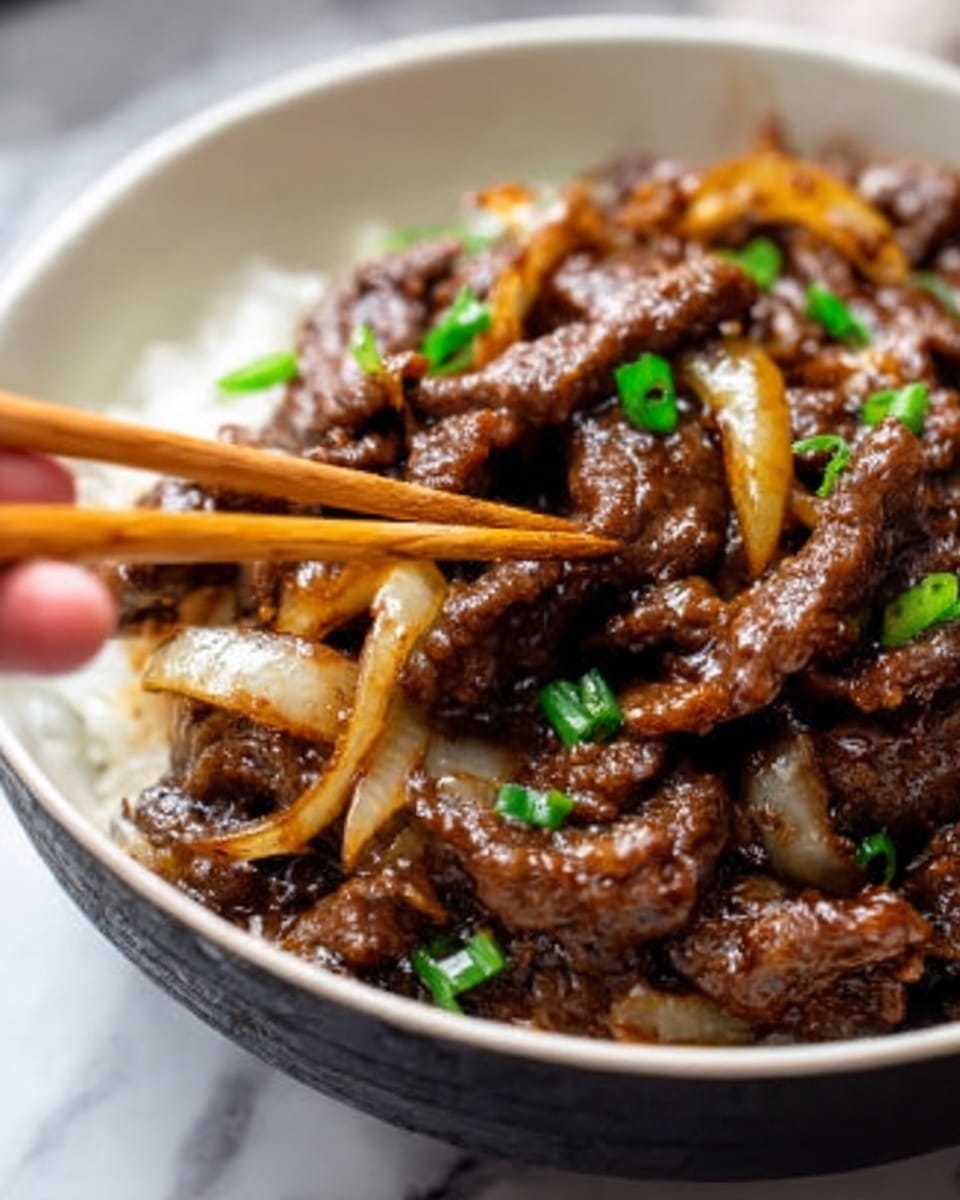 A close-up image shows a white bowl filled with stir-fried beef strips mixed with sliced onions. The beef is dark brown, glossy with sauce, and the onions are slightly translucent with a pale yellow color. A woman's hand holds wooden chopsticks, picking up some beef from the bowl. The background is a white marbled texture. Photo taken with an iphone --ar 4:5 --v 7