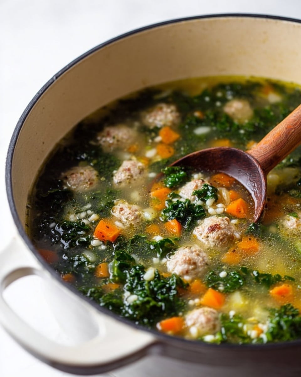 A close-up view of a white cast iron pot filled with clear broth soup containing small light gray meatballs, bright orange diced carrots, dark green leafy kale, and small white grains, all mixed together. A brown wooden spoon is partially submerged on the left side, stirring the soup. The pot has a visible handle at the front and the scene is set on a white marbled surface. photo taken with an iphone --ar 4:5 --v 7