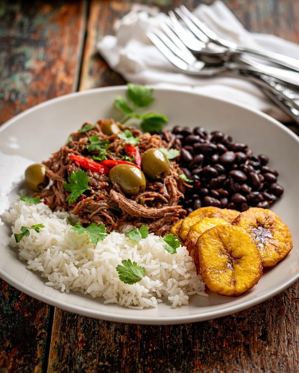 A white round plate with four groups of food arranged in a circle: on the left, white cooked rice with a soft texture and a few green cilantro leaves on top; in the center-left, a pile of shredded brown meat mixed with green olives and small pieces of red pepper, garnished with green cilantro leaves; on the right, a small heap of shiny black beans; and on the far right, two golden-brown fried plantains with a slightly crispy surface; the plate is placed on a rough wooden table with a white cloth and a stack of metal forks in the background, photo taken with an iphone --ar 4:5 --v 7